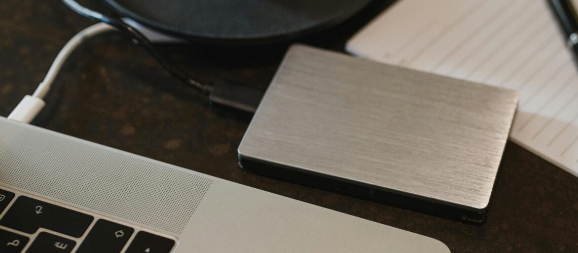 Free Closeup of an external hard drive connected to a laptop with a USB cable on a desk. Stock Photo