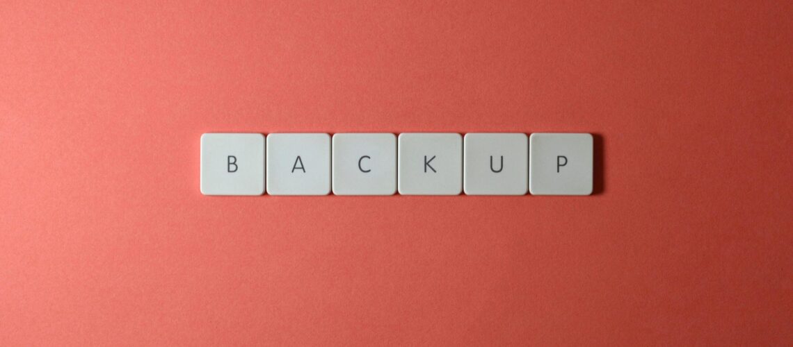 Free Close-up of keyboard keys spelling 'BACKUP' placed on a coral-colored surface. Stock Photo