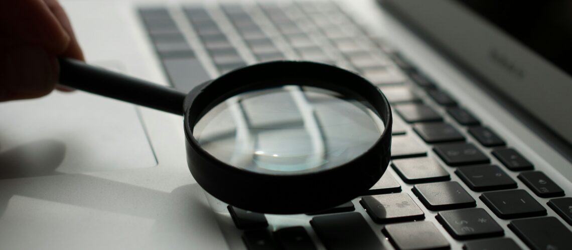 magnifying glass near gray laptop computer